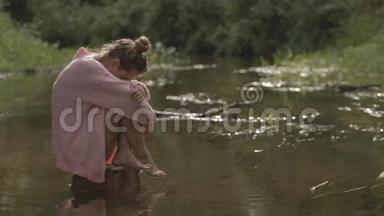 美丽的女孩在森林河的中央戏水