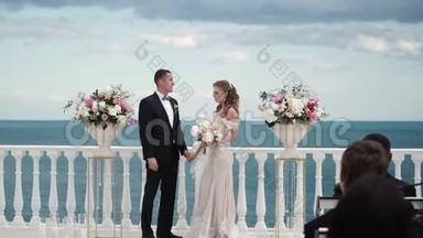 婚礼上的新娘和新郎。 一对相爱的年轻夫妇站在拱门前。 海边的婚礼