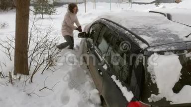 女青年在暴风雪后用刮泥机清洗汽车