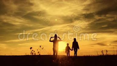 父亲、母亲和孩子徒步旅行的剪影。 婴儿坐在父亲的肩膀上。 徒步旅行背包旅行者徒步旅行
