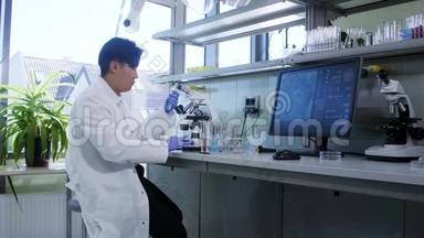 在实验室工作的科学家。 亚洲医生做医学研究。 实验室工具：显微镜、试管、设备