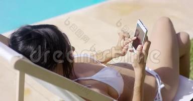 在夏日的阳光下，年轻女子在手机上浏览