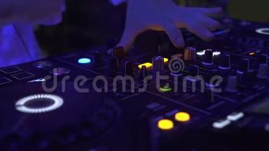 DJ控制音乐控制台和夜总会的彩灯。 DJ在迪斯科晚会的音响控制台播放音乐。 光碟骑师