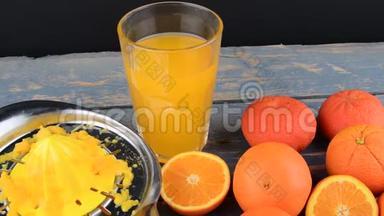 橘子，橘子，一杯橙汁和手动柑橘吱吱在蓝色的木制背景。 橘子切成两半