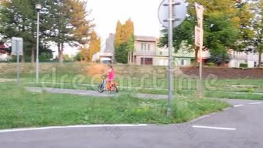 女孩在操场上骑自行车交通。 夏天骑自行车的小女孩