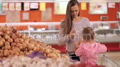 母亲和女儿在超市购物时选择蔬菜