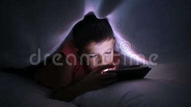 小男孩在<strong>床上玩手机</strong>或智能<strong>手机</strong>。 夜晚