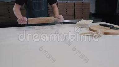 面包师用擀面杖把面团摊开，年轻厨师做披萨送外卖