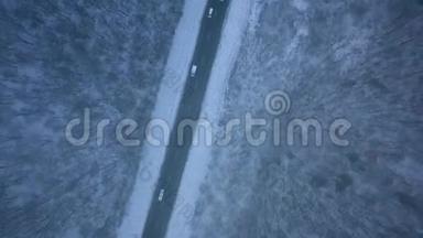 暴风雪中穿过冬季森林的道路上的交通鸟瞰图