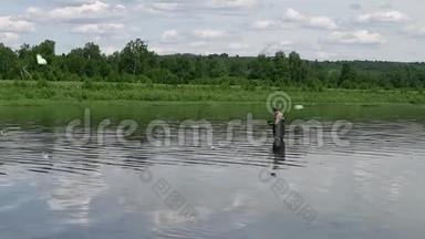 渔夫在一条平静的河里钓鱼。 穿着渔具的人在河里
