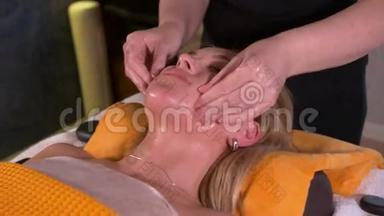 一名年轻女子在美容院接受水疗治疗的特写。 水疗面部按摩。 面部美容治疗。 水疗沙龙。