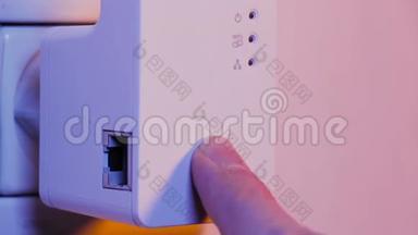 男子用手指按在Wi Fi连接器上的<strong>WPS</strong>按钮上，这是在墙上的电气插座上