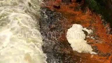 砂岩岩石之间的快速泡沫水，肮脏河岸上的橙色<strong>沉积物</strong>。 深河床成砂岩块状