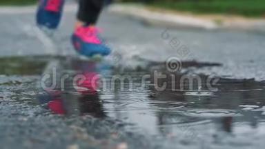穿运动鞋的跑步者的腿的特写镜头。 女运动员<strong>在</strong>公园里慢跑，<strong>踩在</strong>泥泞的<strong>水</strong>坑里。