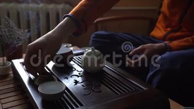 在中国传统的茶道上，人们正在茶壶里倒茶。 一套茶饮设备