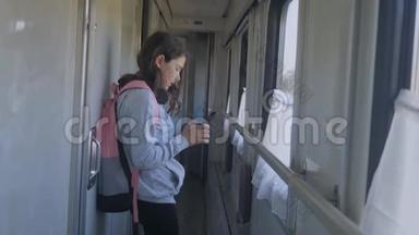 小女孩走在火车车厢里，带着生活方式背包和智能手机。 交通运输