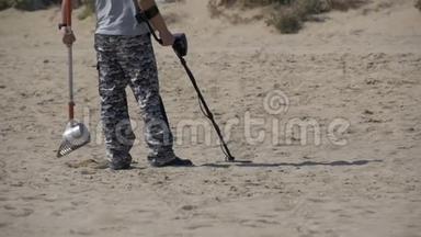 带金属探测器的人沿着海滨的沙滩漫步。 慢动作