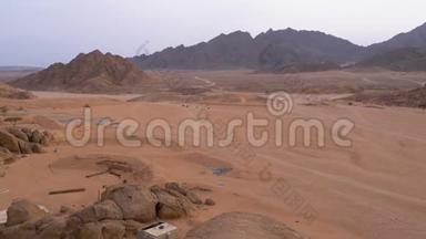 在埃及沙漠中，一列四方自行车在山脉的背景下行驶。 驾驶ATV。