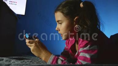青少年女孩在室内玩手提儿童电子游戏，晚上玩游戏机