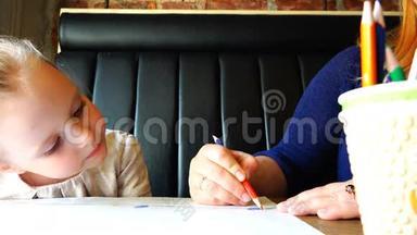母亲和女儿在桌旁的纸上画红铅笔