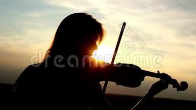 剪影女孩<strong>小提琴</strong>手在日落的天空<strong>背景</strong>下拉<strong>小提琴</strong>。