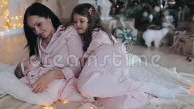 母亲和女儿穿着粉红色睡衣的新生婴儿在<strong>平安</strong>夜
