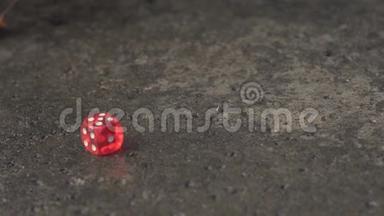 在混凝土板上缓慢滚动的红色骰子