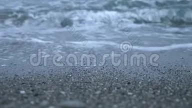 日落时的卵石海滩。 波浪飞溅，碎成飞沫.. 4k，慢动作