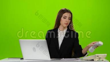 女人接办公室的电话。 绿色屏幕