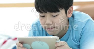 可爱的亚洲男孩在平板电脑上默默地看着和玩。