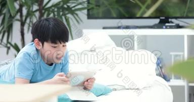 可爱的亚洲男孩在平板电脑上<strong>默默</strong>地看着和玩。