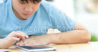 可爱的亚洲男孩在平板电脑上<strong>默默</strong>地看着和玩。