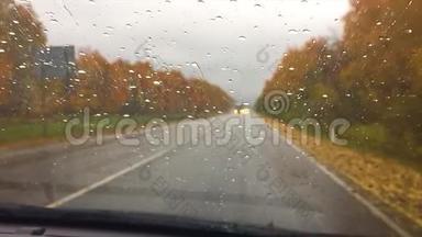 汽车在柏油路上行驶。秋游山林<strong>美景</strong>，雨滴落在玻璃车上模糊背景行车