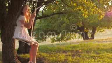 <strong>孩子</strong>们在公园的秋千上<strong>晒太阳</strong>。 年轻女孩在橡木树枝上的绳子上摆动。 少女喜欢飞行