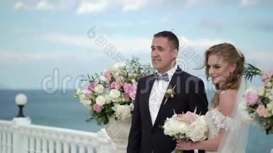 婚礼上的新娘和新郎。 一对相爱的年轻夫妇站在拱门前。 海边的婚礼