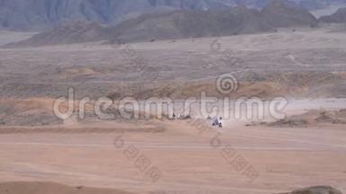 一列四人自行车骑在沙漠在埃及的山脉背景。 驾驶ATV。