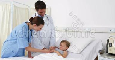 <strong>生病</strong>的<strong>小女孩</strong>躺在床上与护士和医生交谈