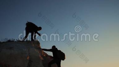 两个男子协同游客爬上一座山。 徒步旅行者徒步旅行冒险登山日落攀登