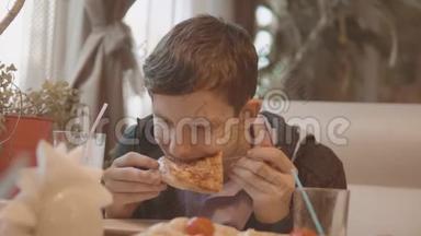 少年在咖啡厅慢动作视频里吃披萨。 他正在吃美味的披萨。 朋友在一家公司吃饭