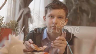 少年在咖啡厅慢动作视频里吃披萨。 他正在吃美味的披萨。 朋友在一家公司吃饭
