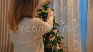 美丽的金发女孩在舒适的晚屋里装扮一棵圣诞树