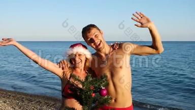 两个戴着圣诞帽的男人和女孩在海滩上迎接新年和圣诞节。 把<strong>圣诞树装饰</strong>在<strong>圣诞树</strong>上