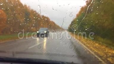 汽车行驶在路上. 秋天旅行美丽的风景林，雨滴在玻璃车上行驶模糊的背景
