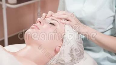 戴着面具和手套的女美容师给一个有魅力的女人做一个有益健康的面部按摩。 新一代