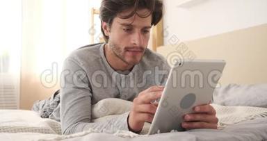男人在家里的床上使用数码平板电脑