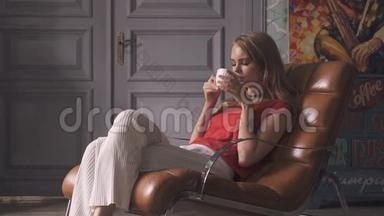 漂亮的年轻女人，家里坐在扶手椅上喝茶。