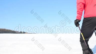 冬季游客带着雪鞋在雪地漂流中行走。 穿着粉色运动夹克的徒步旅行者和穿着雪鞋的黑色徒步旅行者