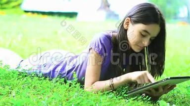 在草地上使用数字平板电脑的少女