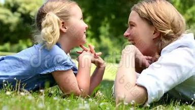 快乐的母亲和她的<strong>小女孩</strong>躺在<strong>草地上</strong>公园里