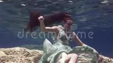在红海珊瑚的背景上，年轻<strong>女孩</strong>模特在水下摆姿势拍照。